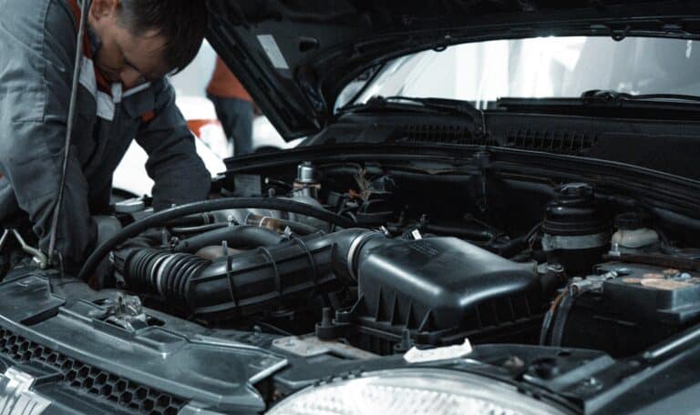 Mecánico certificado inspeccionando el motor de un carro durante una inspección vehicular en Texas