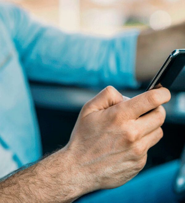 Driver texting on a smartphone with one hand on the steering wheel, illustrating distracted driving