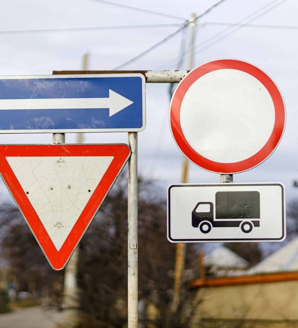 Señales de tránsito incluyendo ceda el paso, sentido único y restricción de camiones en un poste vial